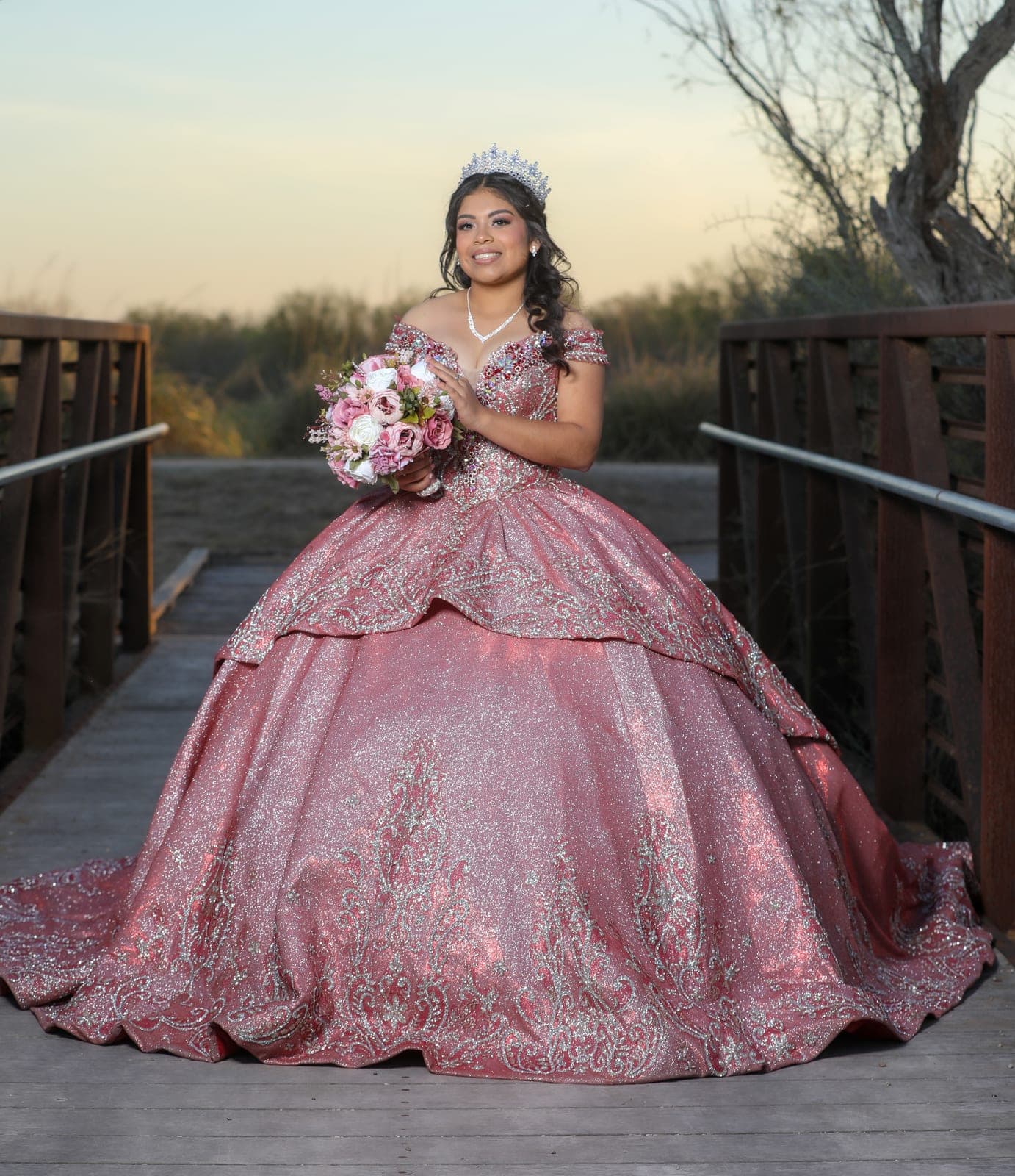 Quinceañera in her rose gown on a bridge