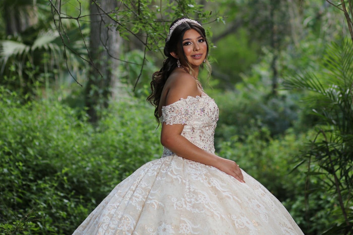 Quinceañera in an ivory ball gown in a garden