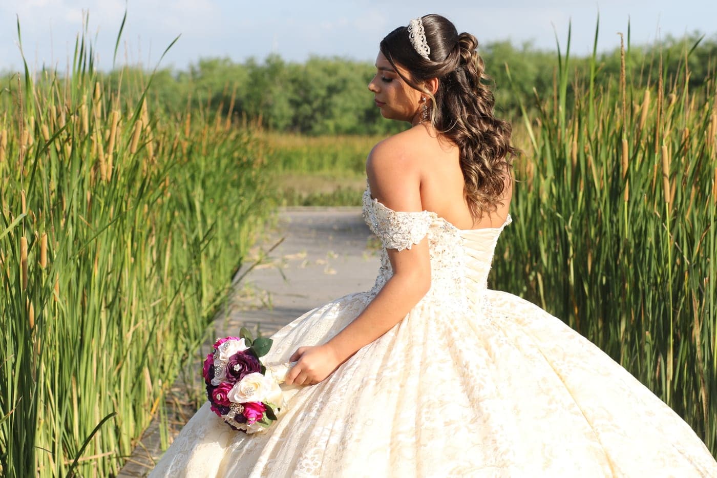 Quinceañera with her bouquet amid greenery