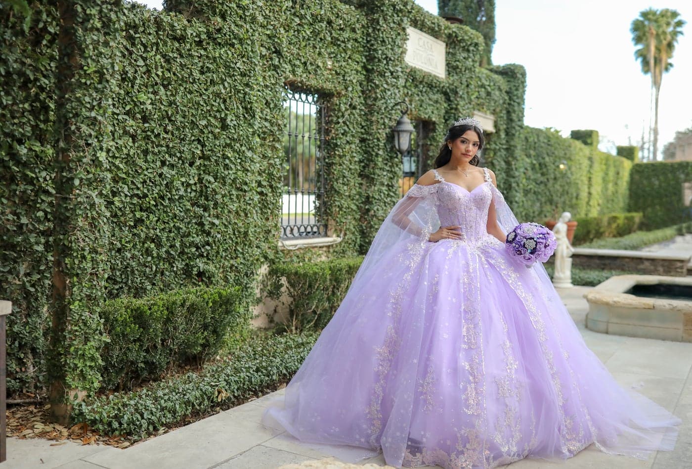 Quinceañera in a lavender gown by an ivy wall