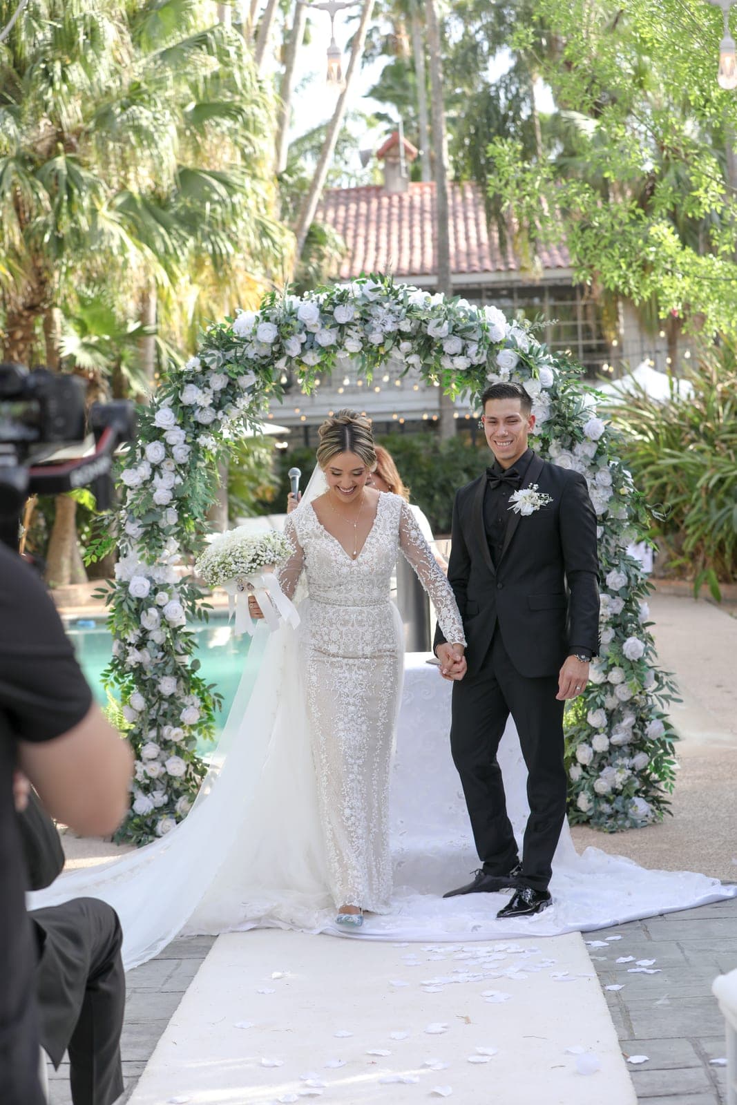 Bride and groom under a floral arch at a Valley wedding