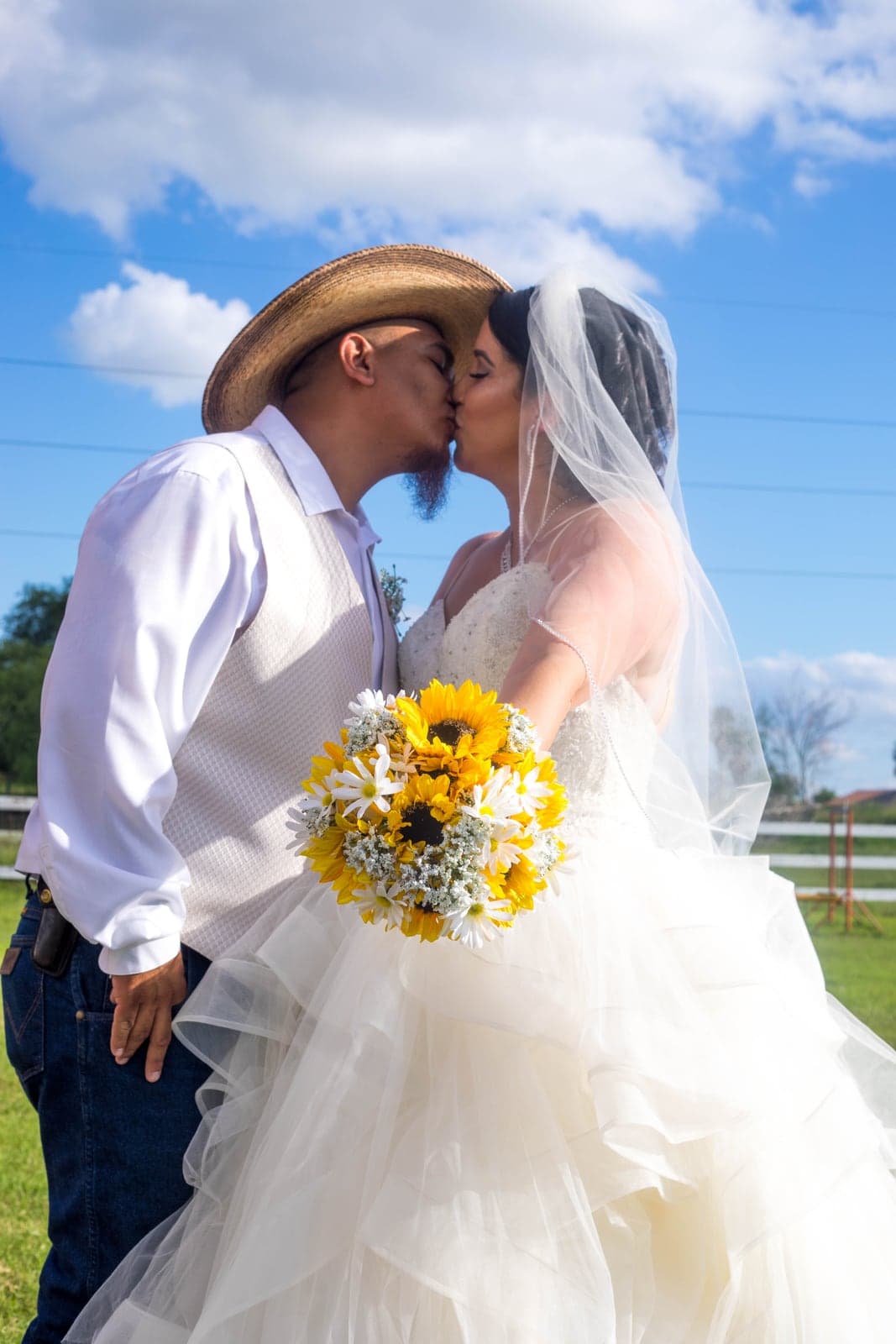 Charro-style couple kissing with sunflowers at a Valley wedding