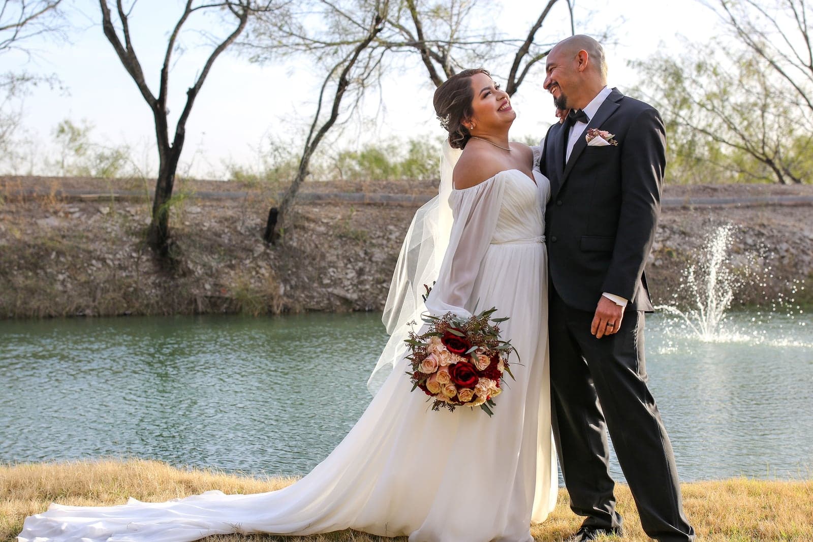 Bride with her bouquet by the water at golden hour
