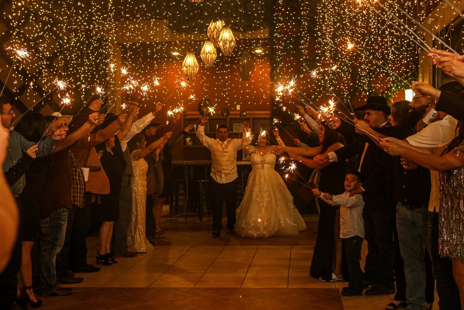 Packed wedding dance floor lit by sparklers and string lights