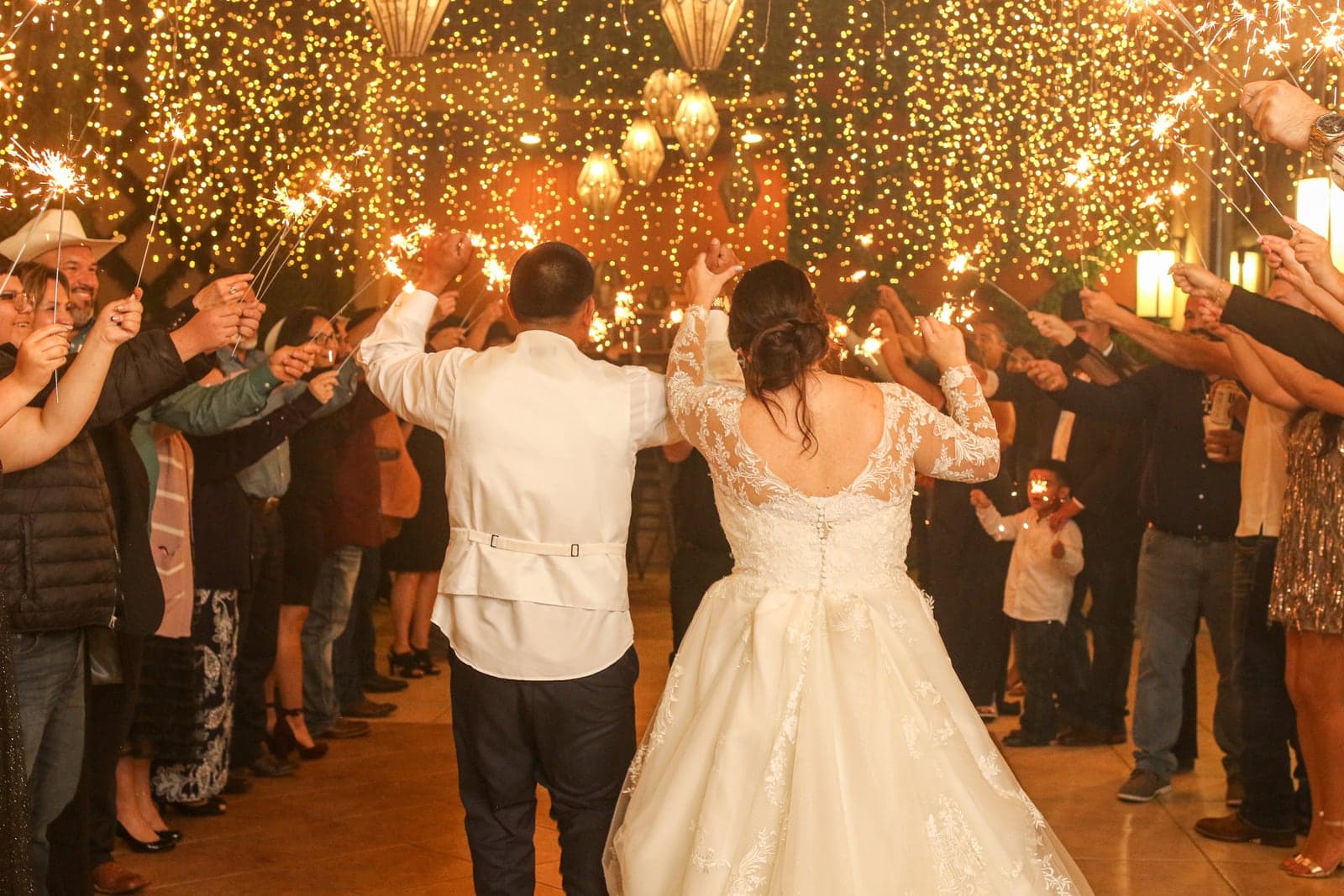 Couple dancing beneath warm string lights at their reception
