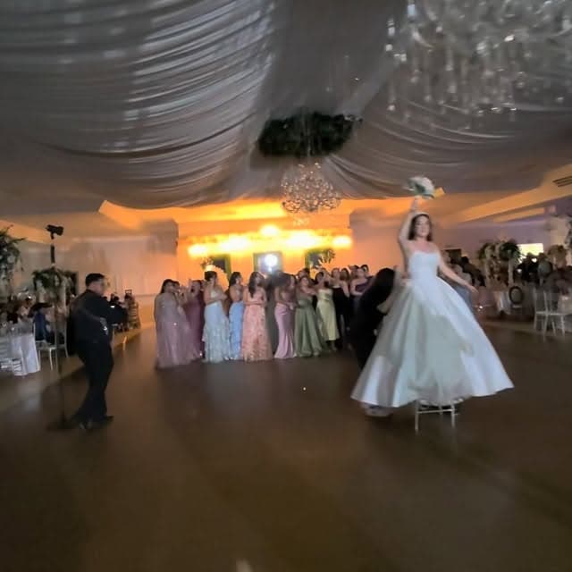 Bouquet toss on a draped, uplit ballroom dance floor