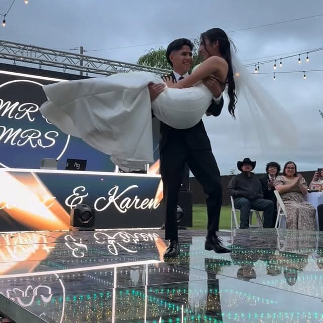 Couple's celebration on a mirrored stage with neon signage