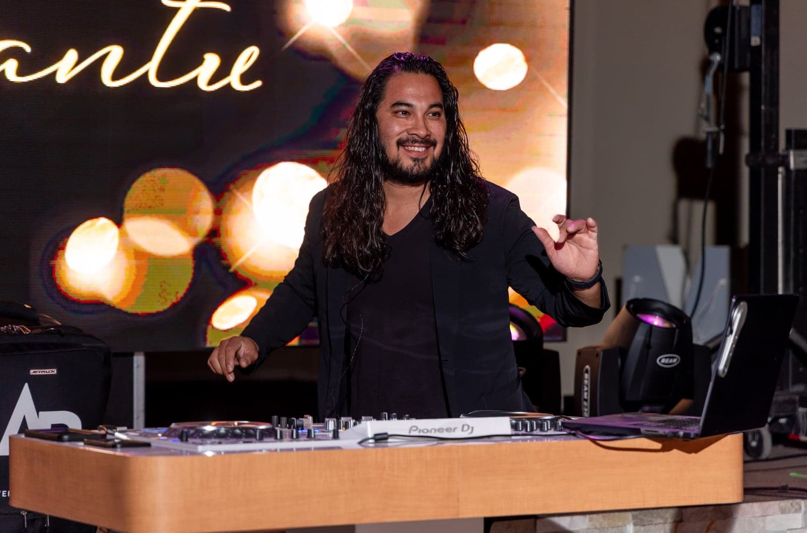Abraham, owner of AB Event Productions, mixing at the Pioneer DJ decks under warm event lighting
