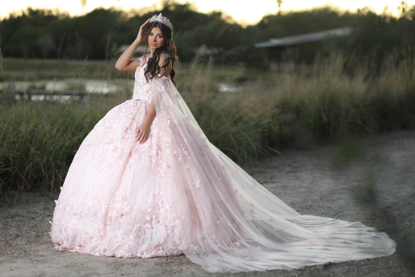 Quinceañera in a blush ball gown with a full train at golden hour
